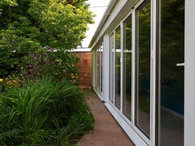 white aluminium bifolding doors going along the side of a house next to the garden